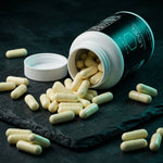 VIGORYS LEVEL Metabolic Primer open bottle with light yellow vegetable capsules spilling onto dark slate surface, showing apple cider vinegar and enzyme blend capsule form
